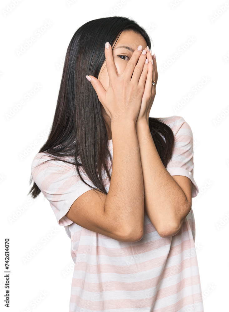 Young Chinese woman in studio setting blink through fingers frightened and nervous. Young Chinese woman in studio setting blink through fingers frightened and nervous.