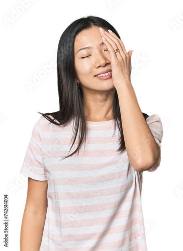 Young Chinese woman in studio setting laughing happy, carefree, natural emotion.