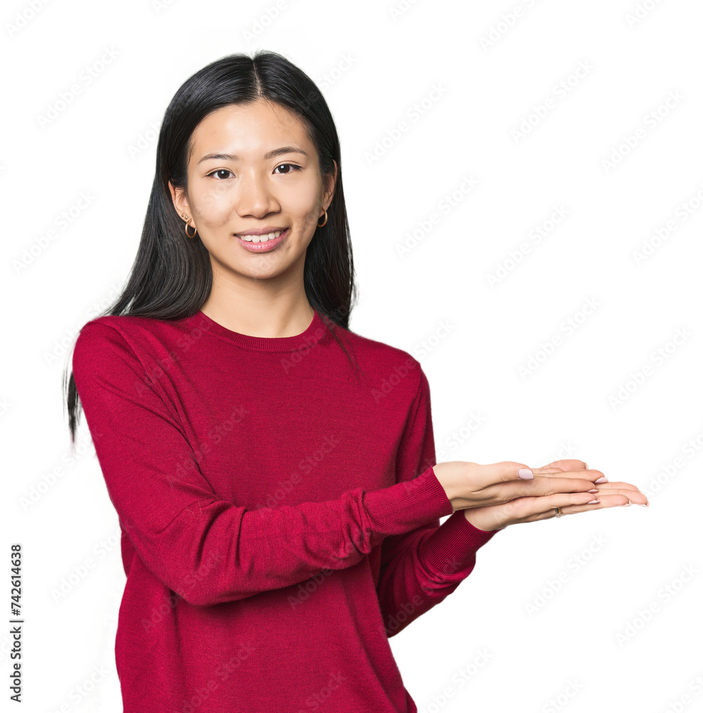 Young Chinese woman in studio setting holding a copy space on a palm. Young Chinese woman in studio setting holding a copy space on a palm.