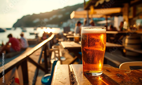 A glass of fresh beer against the backdrop of the blue sea and rocky coast. Top view of a beautiful landscape.