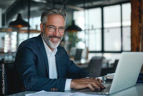 Smiling mature adult business man executive sitting at desk using laptop. Happy busy professional mid aged businessman ceo manager working on computer, Generative AI