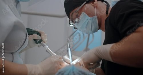 The dental surgeon does the surgery with assistant in stomatological clinic photo