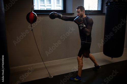 Focused boxer improving punch speed with floor to ceiling bag photo