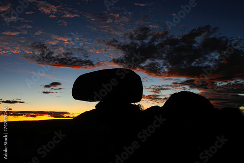 Silhouette of the Devils Marbles (Karlu Karlu in Aboriginal language) at sunset in the Australian Red Center, Northern Territory - Granite boulders formed by erosion and natural weathering in bushland photo
