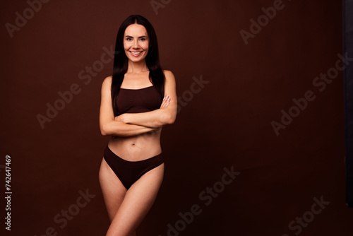 Photo of stunning cheerful sportive girl crossed hands perfect figure empty space isolated on brown color background © deagreez