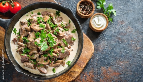 delicious beef stroganoff veal strips stewed with porcini in sour cream sauce sprinkled with finely chopped parsley on skillet authentic recipe view from above