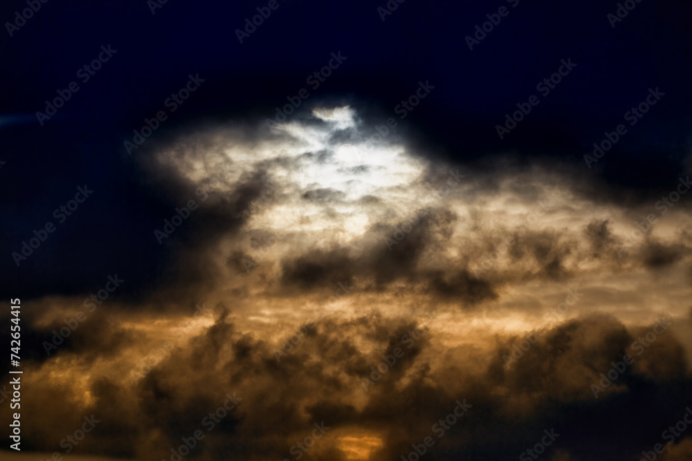 Obraz premium Evening sunlight breaks through dark clouds, gloomy light in the sky