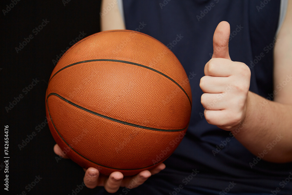 basketball player’s hand holding a basketball with one hand, and the other hand showing a thumbs up. Sports victory in basketball, invitation to a basketball match basketball player’s hand holding a basketball with one hand, and the other hand showing a thumbs up. Sports victory in basketball, invitation to a basketball match