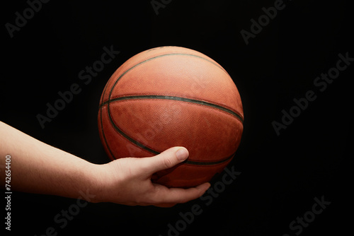 hand holds a lit basketball on a black background, close-up, the start of the game, sports background © Александр Ланевский