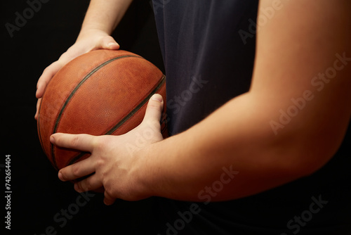 The hands of a basketball player hold the ball to the side, shielding the ball in basketball, basketball training
