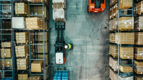 Aerial view of worker driving forklift in warehouse. Retail warehouse with shelves with goods in cardboard boxes. Product distribution logistics center. photo