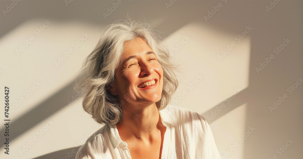 Portrait of happy elegant mature woman with gray hair, standing in sunshine and laughing Portrait of happy elegant mature woman with gray hair, standing in sunshine and laughing