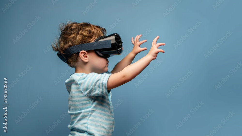 A little boy wears a VR headset and reaches out while testing out augmented technology. A little boy wears a VR headset and reaches out while testing out augmented technology.