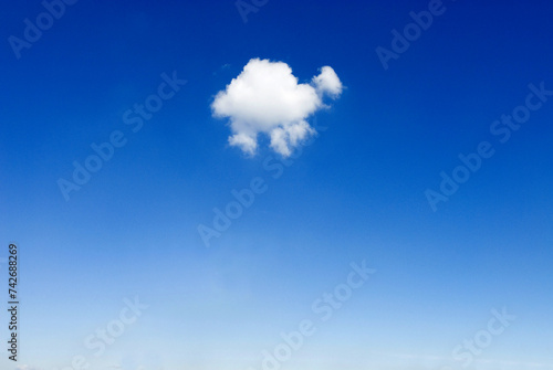 Fototapeta Naklejka Na Ścianę i Meble -  one single small fluffy white fair weather cloud in blue sky