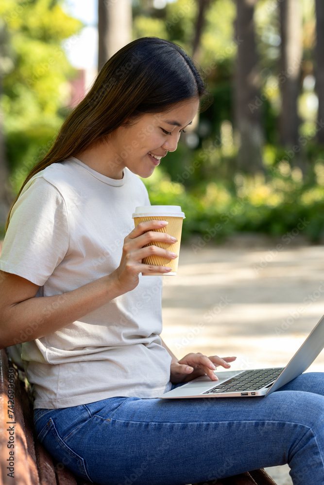 Profile view of a young student working on a laptop in the university campus park Profile view of a young student working on a laptop in the university campus park