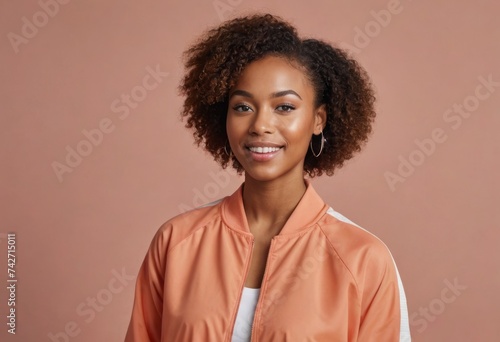 A smiling woman in a casual orange jacket exuding warmth and comfort against a soft background.