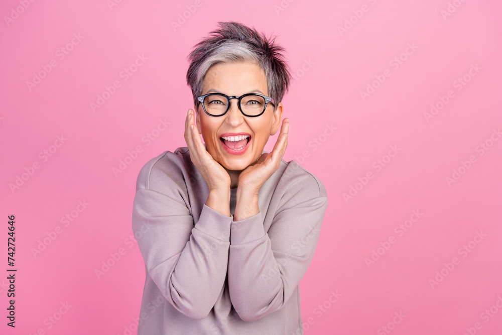 Photo of retired woman in purple sweatshirt business lady touch cheek when realize her project succeeded isolated on pink color background
