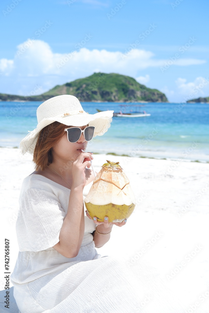 an Asian girl in a cute beach dress is on holiday at the beach while ...