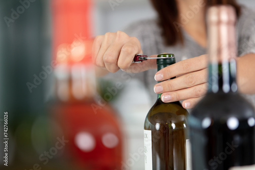 hands opening bottle of red wine with a corkscrew