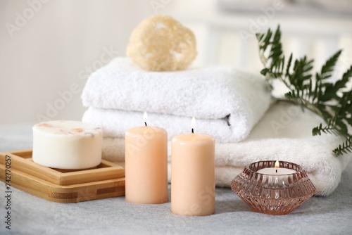 Spa composition. Burning candles  soap  towels and loofah on soft grey surface