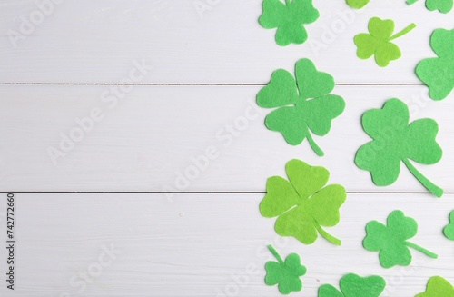 St. Patrick s day. Decorative green clover leaves on white wooden table  flat lay. Space for text