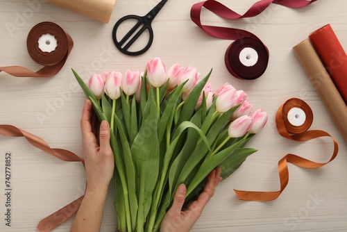 Woman making bouquet of beautiful fresh tulips at white wooden table  top view