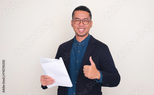 Asian businessman smiling happy and give thumb up while holding report document photo