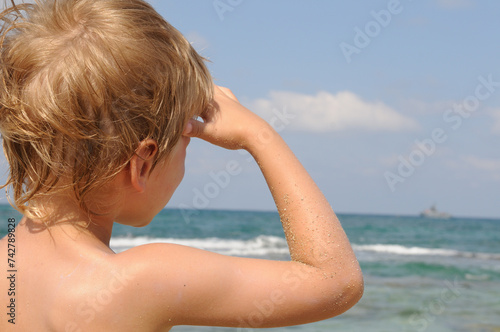 A boy watches a ship sailing to the sea © Benjamin Gelman