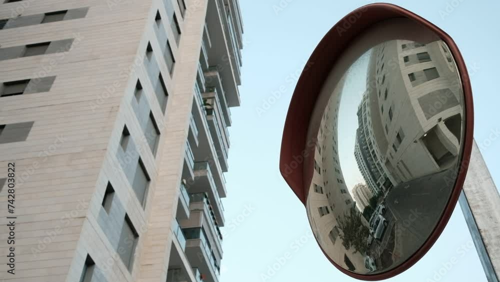 An abstract low angle view, of a rounded mirror, amongst high rise ...