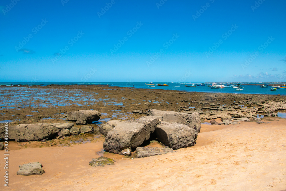 beach with cloudless blue sky and large ruins stones