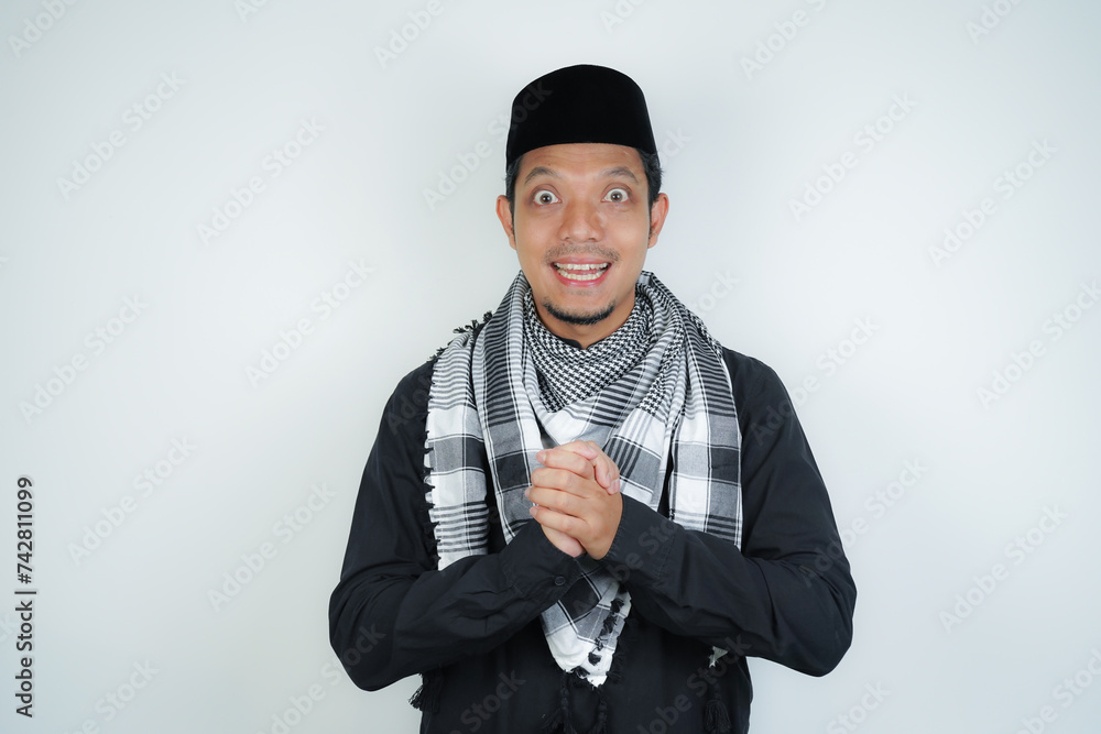 Happy smiling Asian Muslim man in Arabic turban sorban standing with Eid greeting gesture and welcoming Ramadan isolated background Happy smiling Asian Muslim man in Arabic turban sorban standing with Eid greeting gesture and welcoming Ramadan isolated background