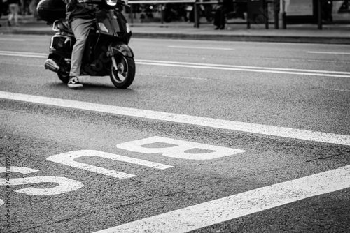 Motorcycle circulating through one of the busiest streets in the city, next to a bus sign.