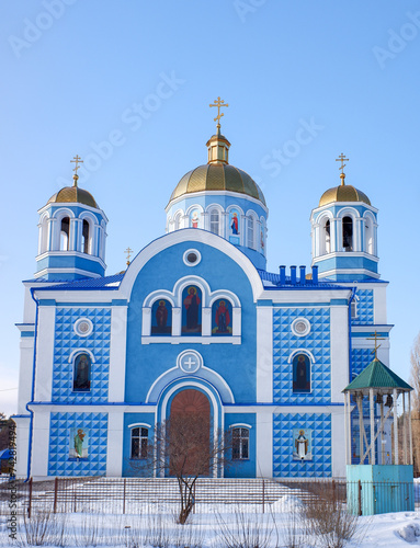 Orthodox church in the forest in winter against the background of a blue sky in sunny weather
