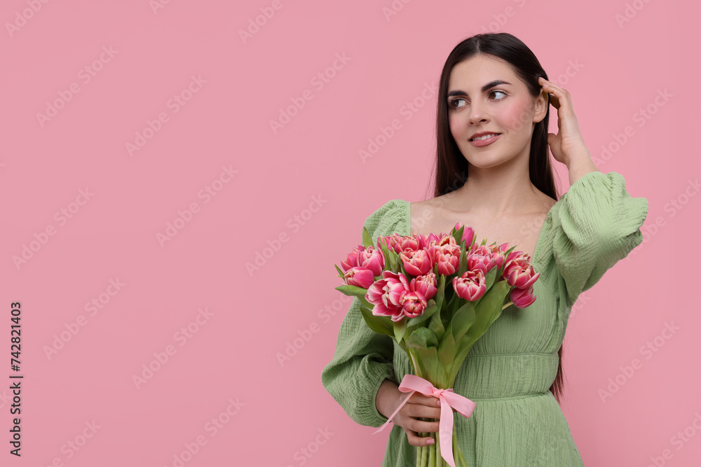 Happy young woman with beautiful bouquet on dusty pink background. Space for text Happy young woman with beautiful bouquet on dusty pink background. Space for text