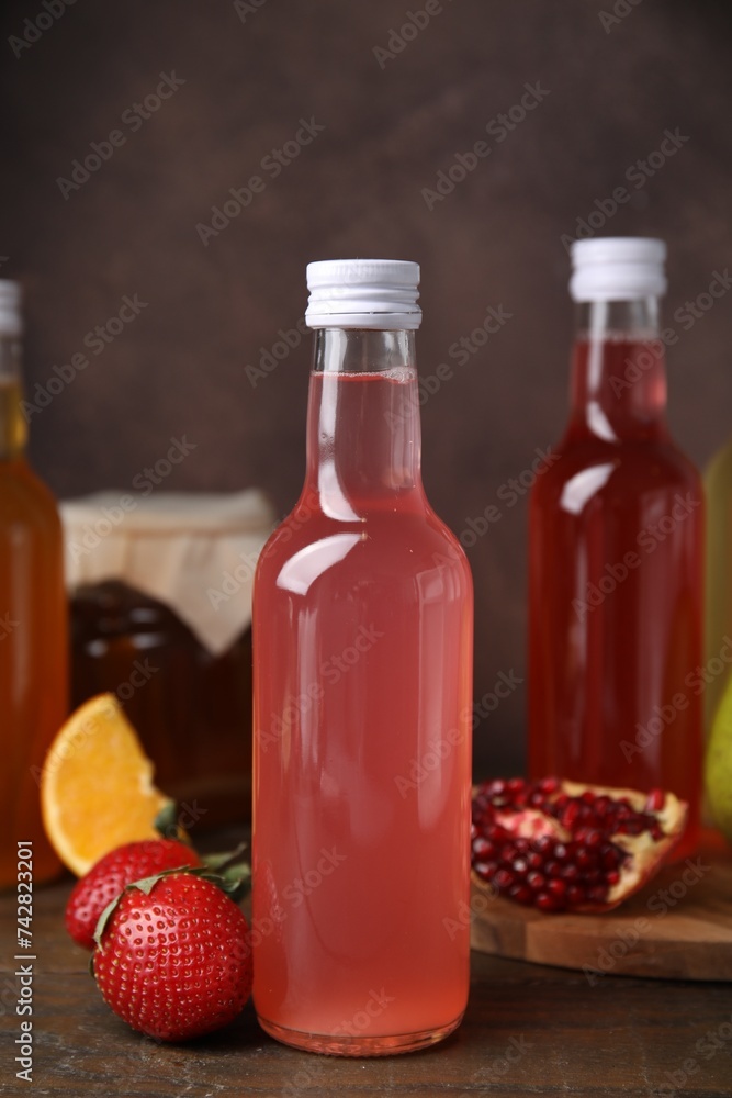 Delicious kombucha in glass bottles and fresh fruits on wooden table Delicious kombucha in glass bottles and fresh fruits on wooden table