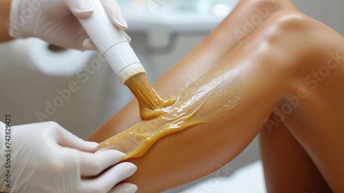 waxing legs, cosmetologist's hands remove hair from girl's skin, beauty salon, sugaring, smooth, self-care, lifestyle, spa salon, shins, knees, woman photo