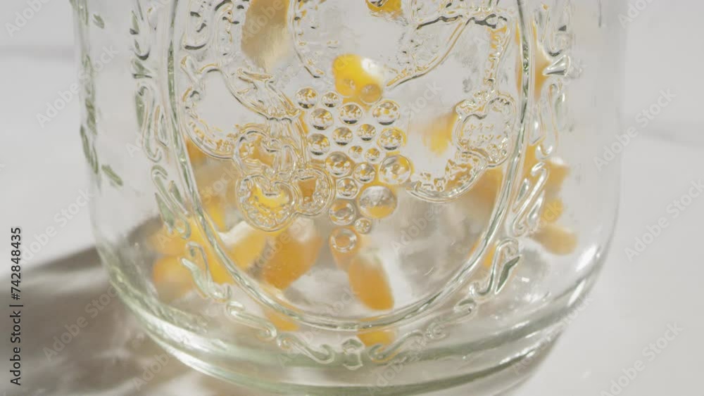 Pouring popcorn kernels into a mason jar in slow motion Pouring popcorn kernels into a mason jar in slow motion