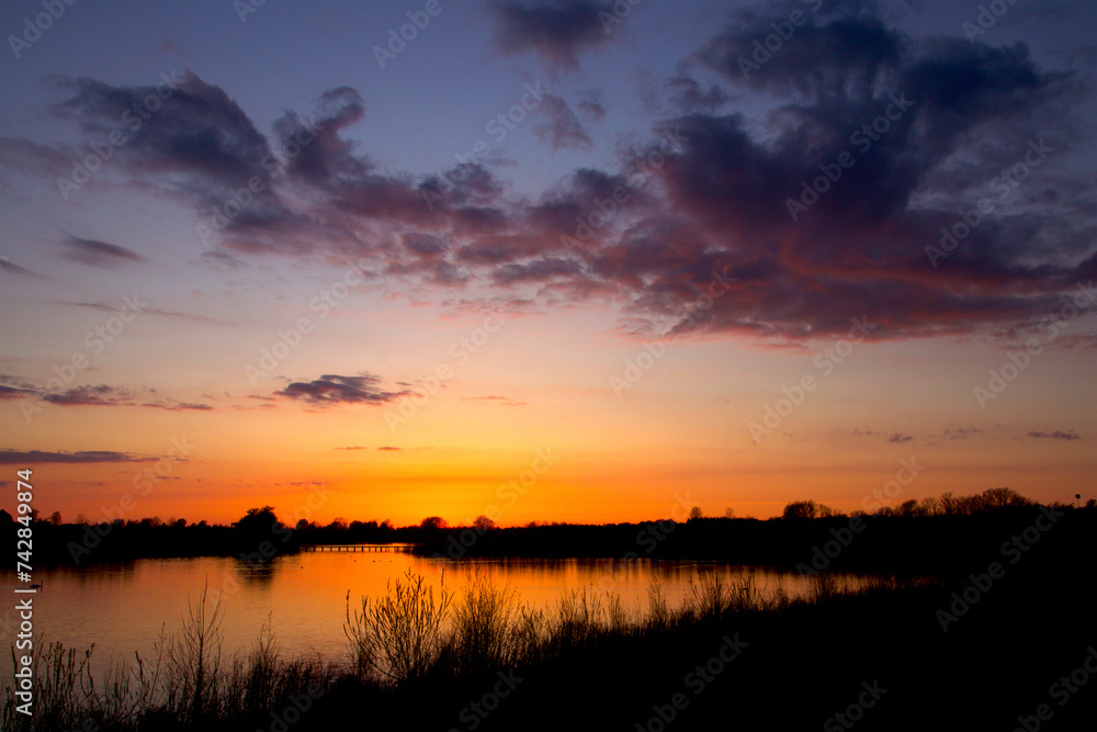 Obraz premium Dusk by the lake in a golden glow and colorful clouds