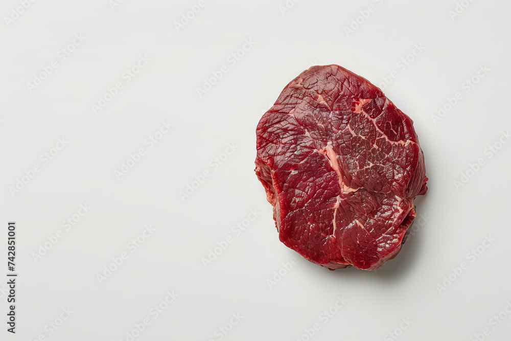 A raw Ribeye steak. Raw meat. White color background, top view. Space for text. A raw Ribeye steak. Raw meat. White color background, top view. Space for text.