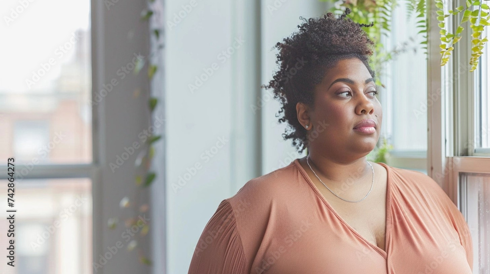 copy space, stockphoto, Plus size Black Woman standing in front of a window. Beautiful woman standing in front of a window in her home, watching outside. Big is beautiful. Body inclusive theme. Heavy copy space, stockphoto, Plus size Black Woman standing in front of a window. Beautiful woman standing in front of a window in her home, watching outside. Big is beautiful. Body inclusive theme. Heavy
