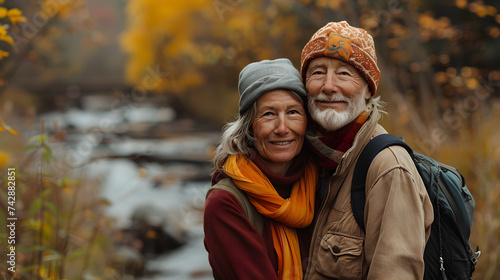 Senior Couple Enjoying Autumn River View with Backpacks photo