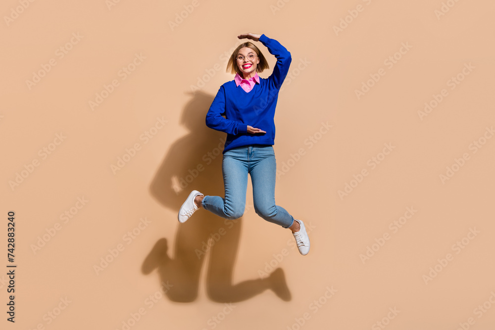 Full body length size photo of funny young business lady measure her height when jumping trampoline isolated on beige color background