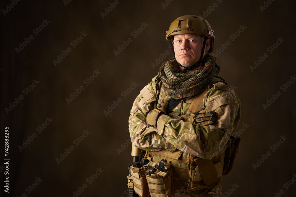 A young male military soldier posing with automatic airsoft rifle with telescopic sighting A young male military soldier posing with automatic airsoft rifle with telescopic sighting