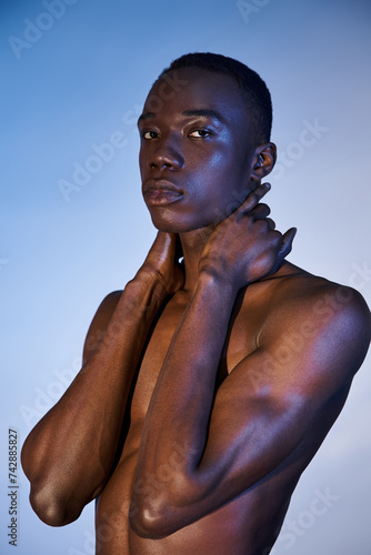 attractive shirtless african american man in fashionable jeans looking at camera on watery backdrop