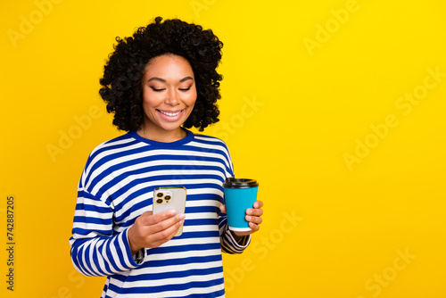 Photo of adorable charming girl wear trendy clothes read social media drink latte break pause empty space isolated yellow color background © deagreez