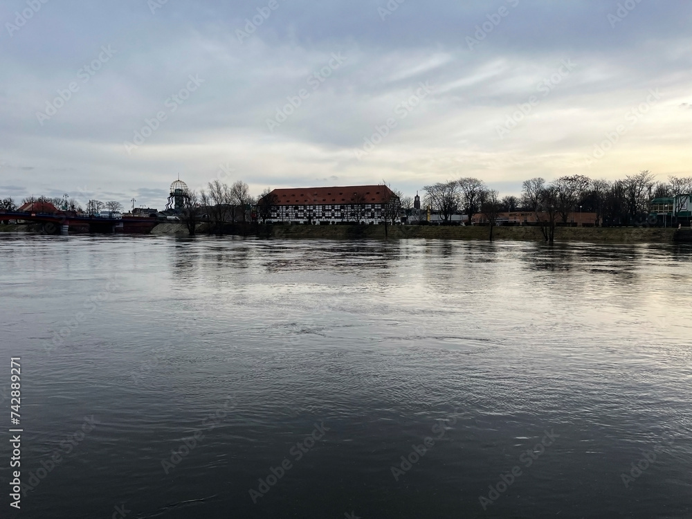 Poland, Gorzow Wielkopolski, 18 February 2024: View of the Warta River, bridge White Barn - a monument of the 18th century, now a branch of the Lubusz Museum. Warta River flood. Flooded shores.
