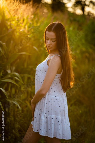 Young beautiful woman in white dress in corn field.