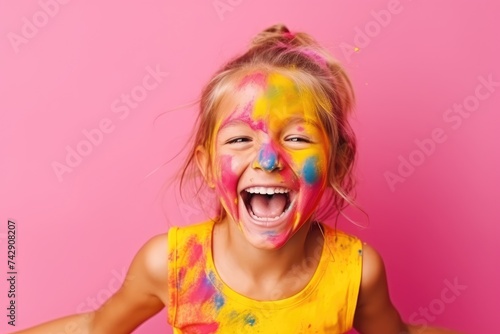 A cheerful young girl shows her hands covered with multicolored paint, her joy unmistakable against a pink background.