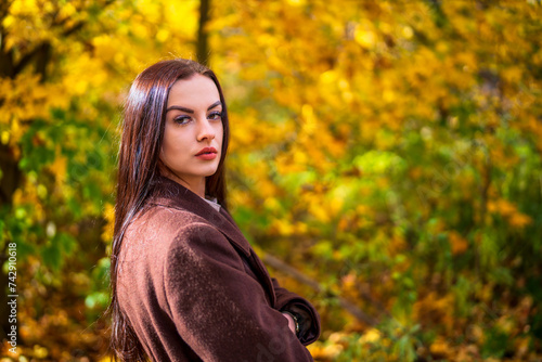Young beautiful woman in brown coat in the park in autumn