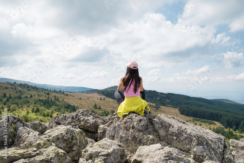 Woman sitting on a rocks looking the city of Sofia in the summer mountain	